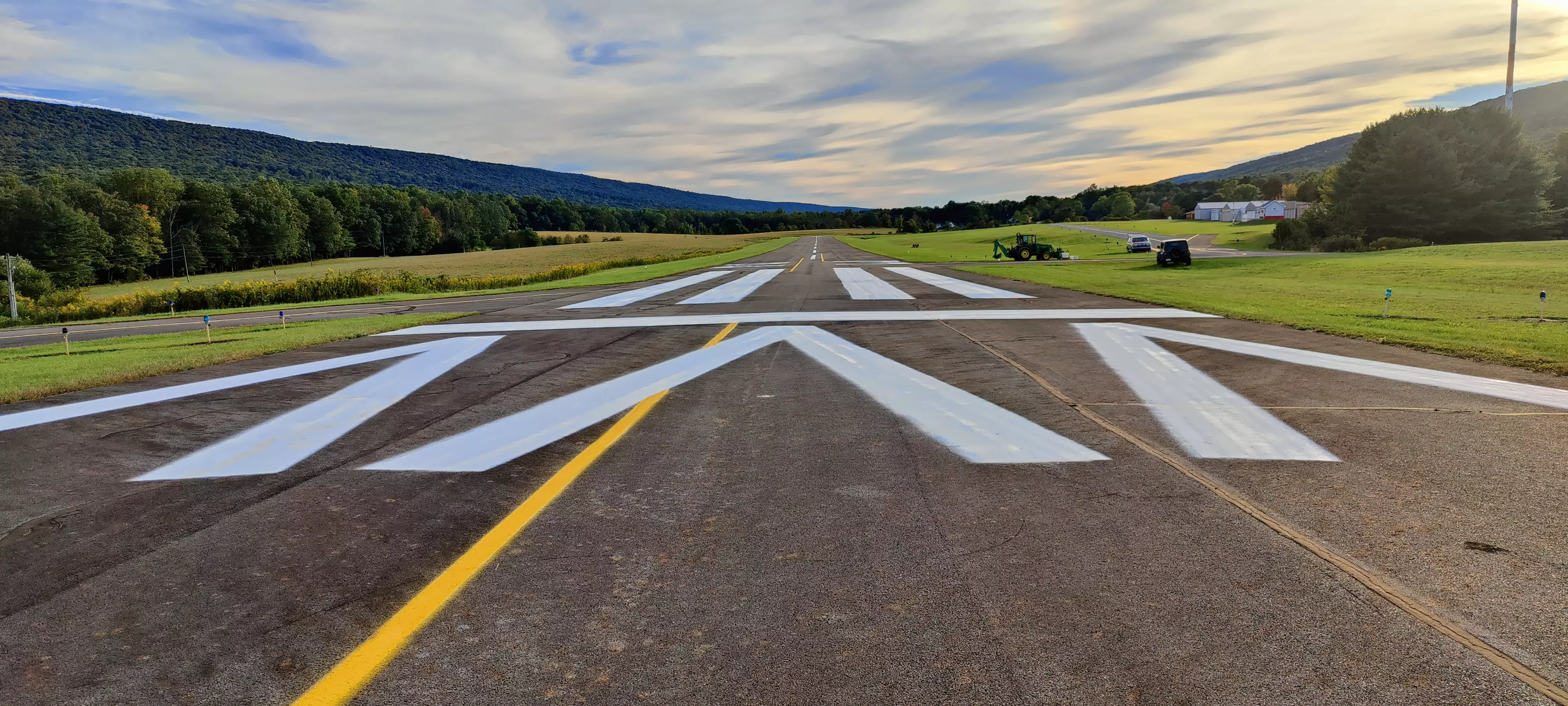 An image of a rural airport runway that lies in a valley between two mountains.